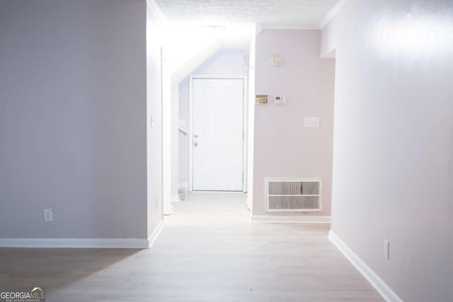 hall featuring light hardwood / wood-style flooring, a textured ceiling, and ornamental molding