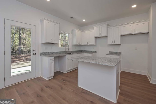 kitchen with a center island, white cabinets, and light stone countertops