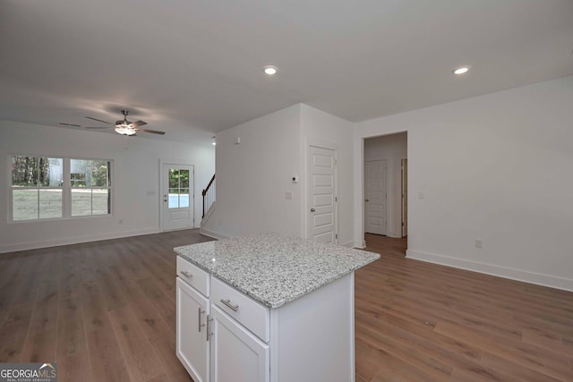 kitchen featuring dark wood-style floors, white cabinetry, open floor plan, and light stone counters