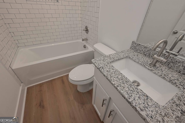 bathroom featuring toilet, bathtub / shower combination, wood finished floors, and vanity