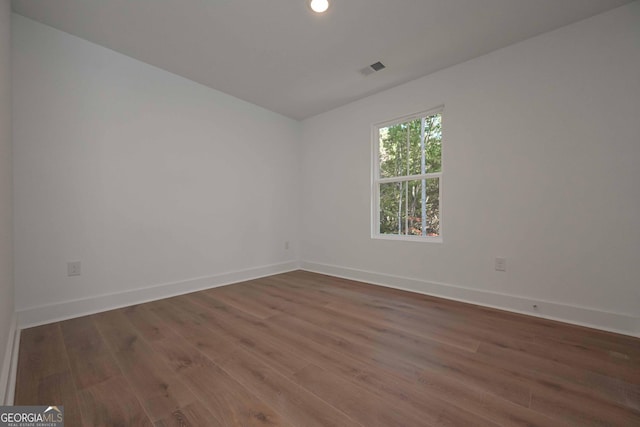 unfurnished room featuring dark wood finished floors, visible vents, and baseboards