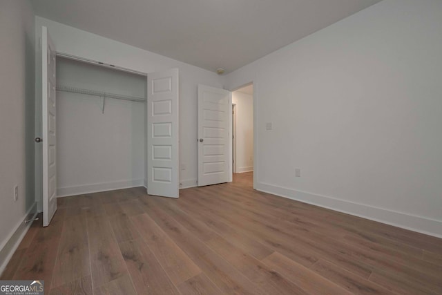 unfurnished bedroom with a closet, baseboards, and wood finished floors