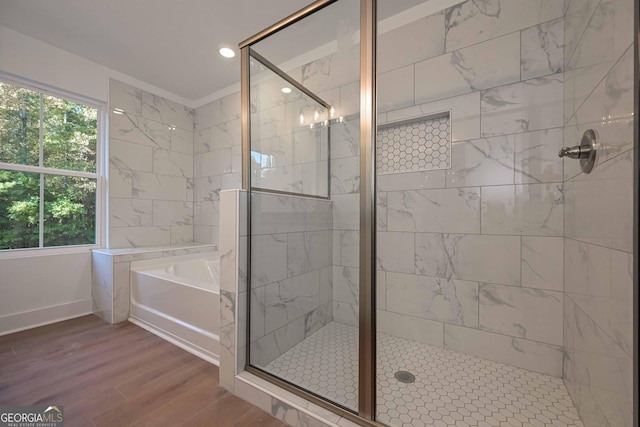 full bath with a stall shower, plenty of natural light, a bath, and wood finished floors