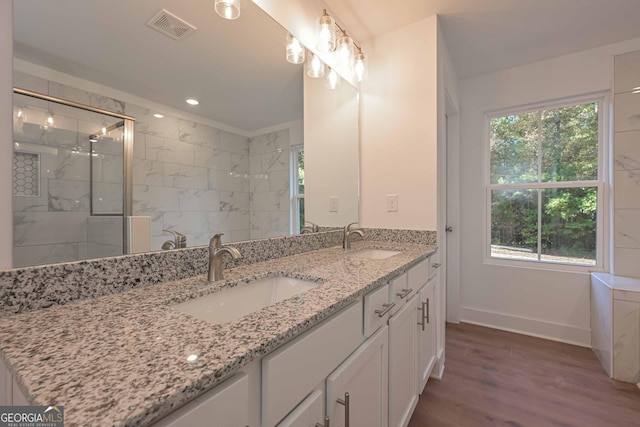 full bath featuring a marble finish shower, wood finished floors, a sink, and visible vents