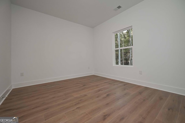 empty room featuring dark wood-type flooring, visible vents, and baseboards