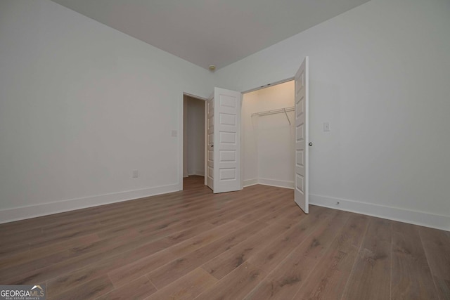 unfurnished bedroom featuring a closet, wood finished floors, and baseboards