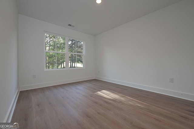 unfurnished room featuring visible vents, dark wood finished floors, and baseboards