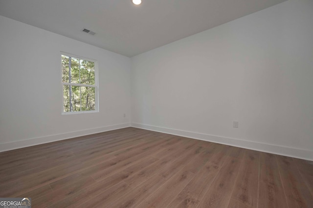 unfurnished room with dark wood-style floors, baseboards, and visible vents