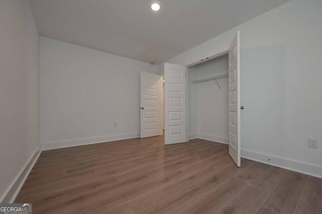 unfurnished bedroom with a closet, dark wood finished floors, and baseboards