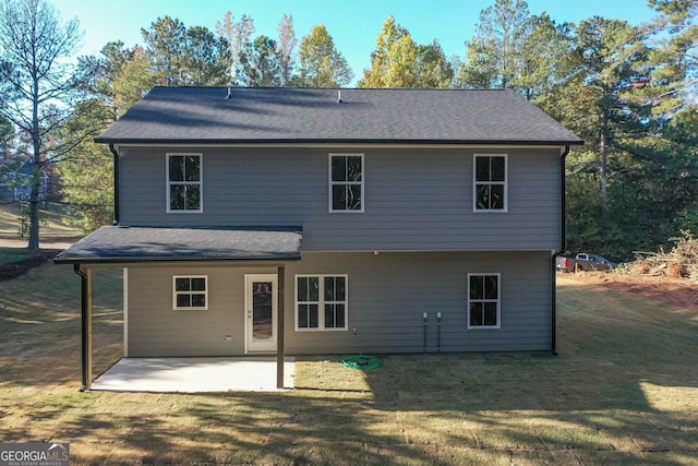 back of property featuring a yard, a shingled roof, and a patio area