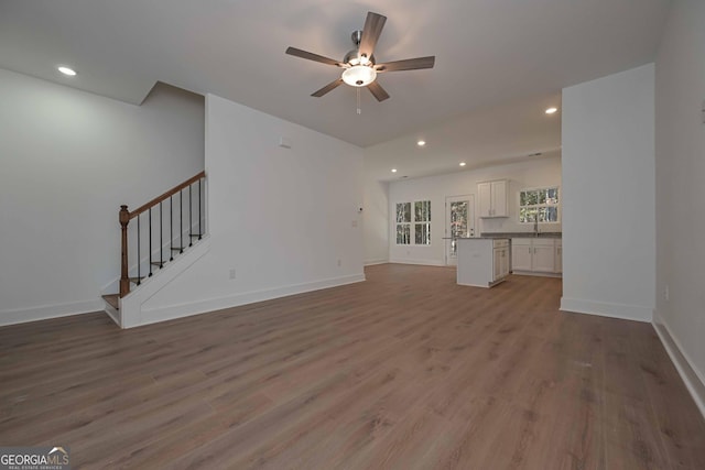 unfurnished living room with stairs, baseboards, wood finished floors, and recessed lighting