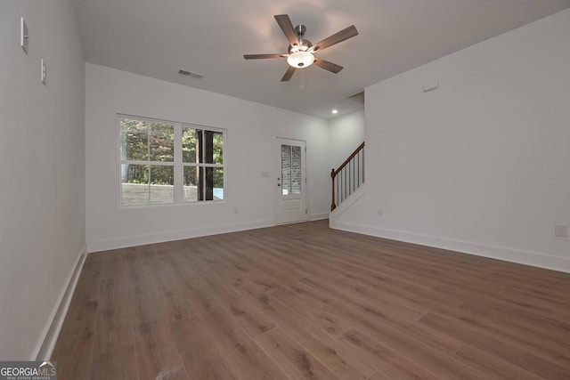 unfurnished living room with visible vents, dark wood finished floors, stairway, and baseboards