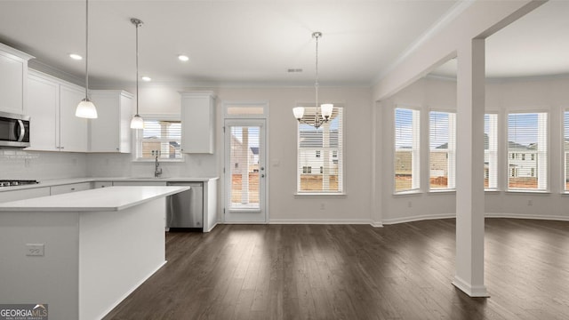 kitchen featuring hanging light fixtures, stainless steel appliances, white cabinetry, and a wealth of natural light