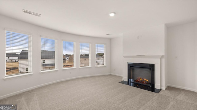 unfurnished living room featuring light colored carpet and a wealth of natural light