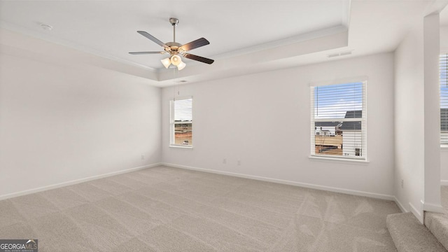 empty room featuring ceiling fan, crown molding, light carpet, and a tray ceiling