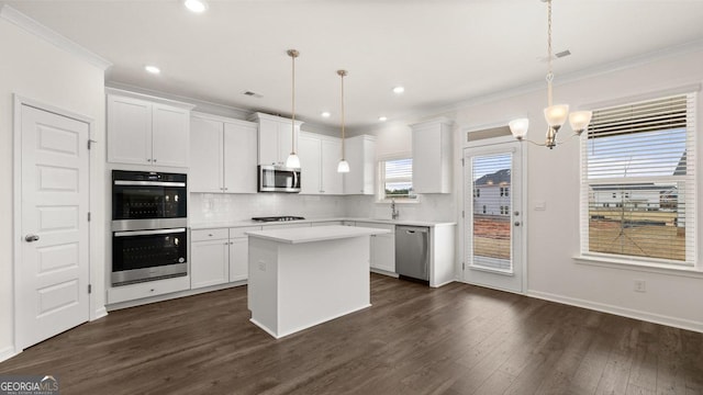 kitchen featuring a center island, decorative light fixtures, stainless steel appliances, and a healthy amount of sunlight