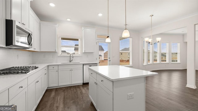 kitchen with dark wood-type flooring, white cabinets, decorative light fixtures, a kitchen island, and appliances with stainless steel finishes