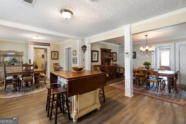 kitchen featuring pendant lighting, dark hardwood / wood-style flooring, crown molding, and an inviting chandelier