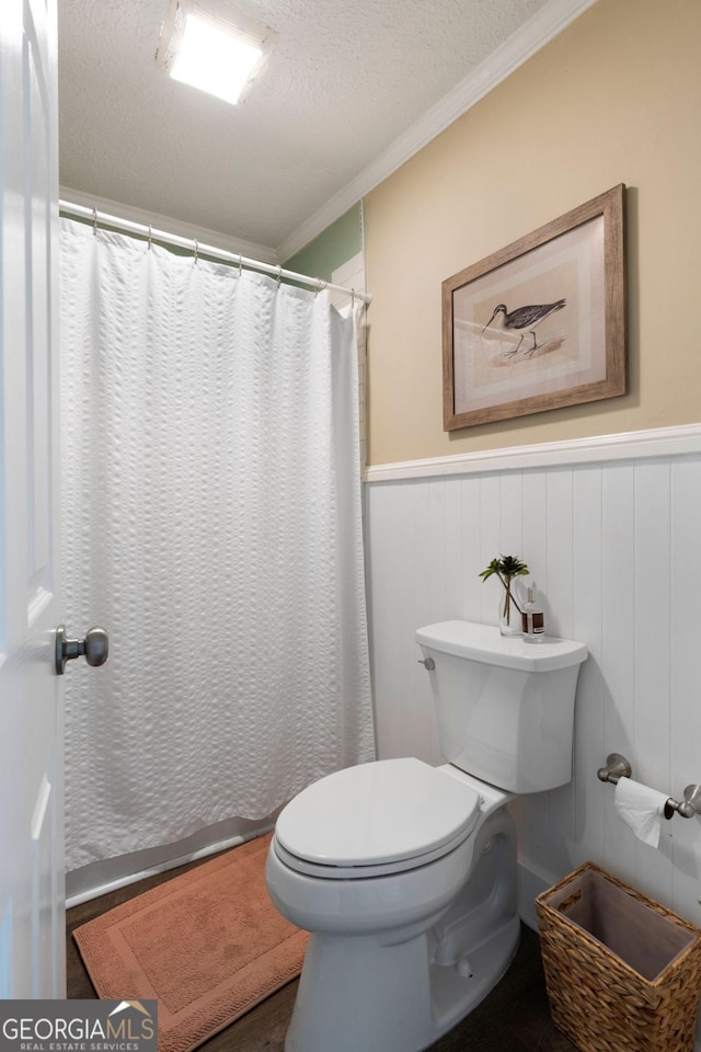 bathroom featuring a shower with curtain, toilet, ornamental molding, and a textured ceiling