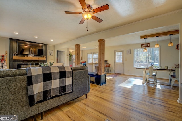 living room featuring ornate columns, hardwood / wood-style floors, ceiling fan, crown molding, and a textured ceiling