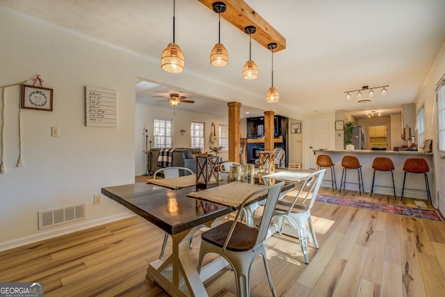 dining area featuring ceiling fan, ornamental molding, a large fireplace, and light wood-type flooring