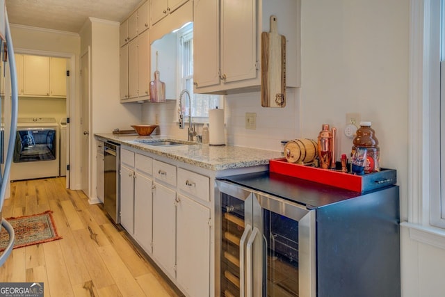 kitchen featuring white cabinetry, sink, stainless steel dishwasher, independent washer and dryer, and light hardwood / wood-style floors