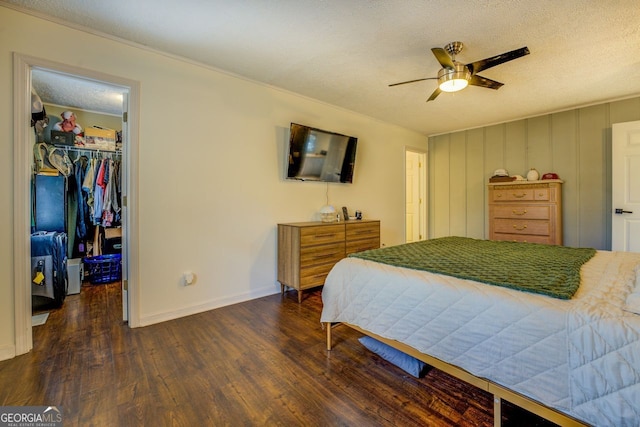 bedroom featuring dark hardwood / wood-style flooring, a walk in closet, ceiling fan, a textured ceiling, and a closet