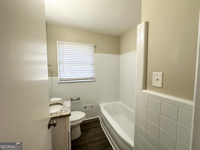 bathroom with a tub, wood-type flooring, toilet, vanity, and tile walls