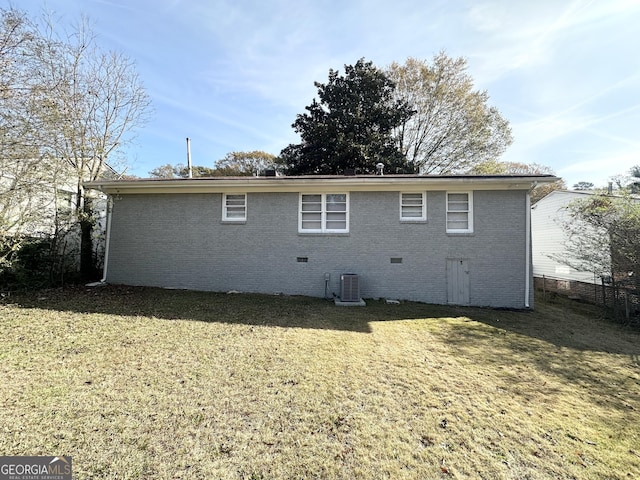 rear view of property featuring cooling unit and a lawn