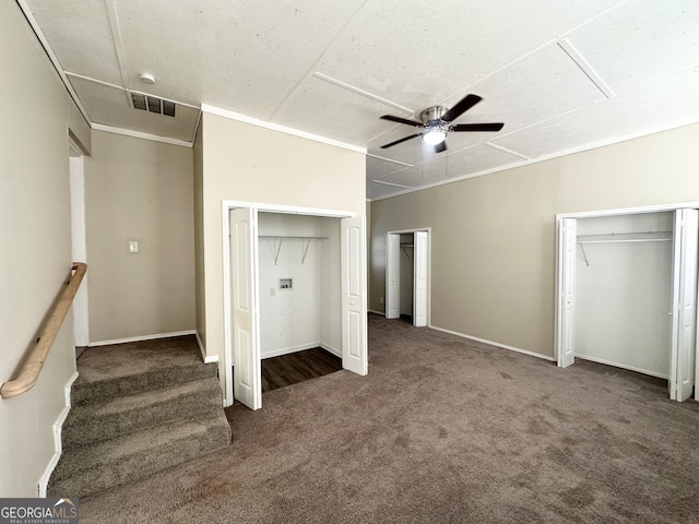 unfurnished bedroom with multiple closets, ceiling fan, and dark colored carpet