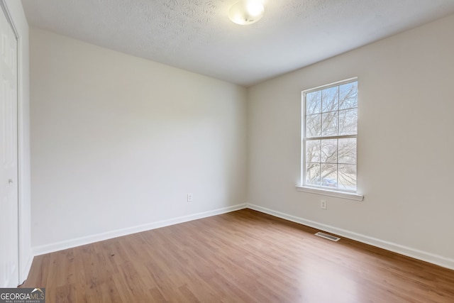 empty room with wood-type flooring and a textured ceiling