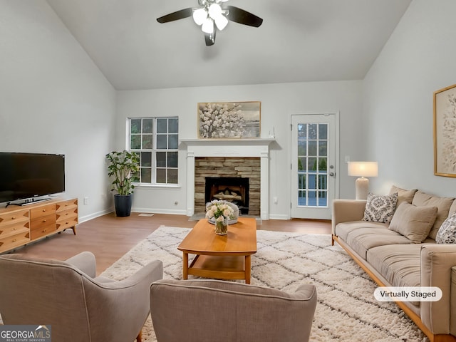 living room featuring a fireplace, a healthy amount of sunlight, light hardwood / wood-style flooring, and vaulted ceiling