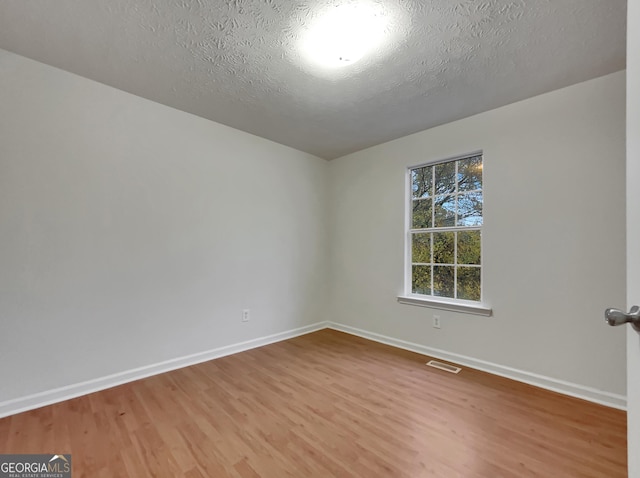 unfurnished room with a textured ceiling and hardwood / wood-style flooring