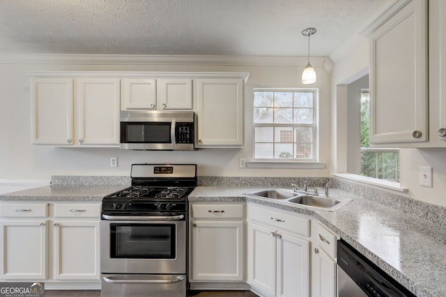 kitchen with a textured ceiling, stainless steel appliances, sink, pendant lighting, and white cabinets