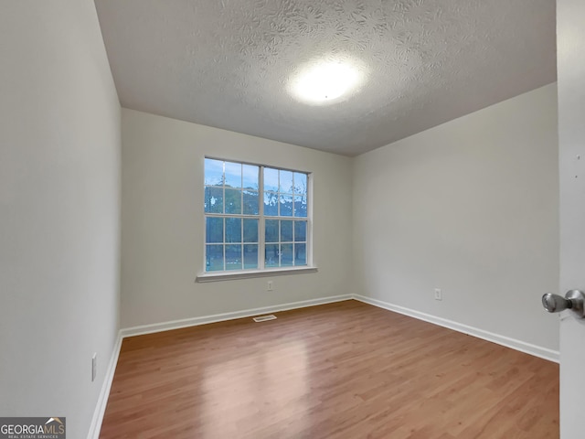 spare room featuring wood-type flooring and a textured ceiling