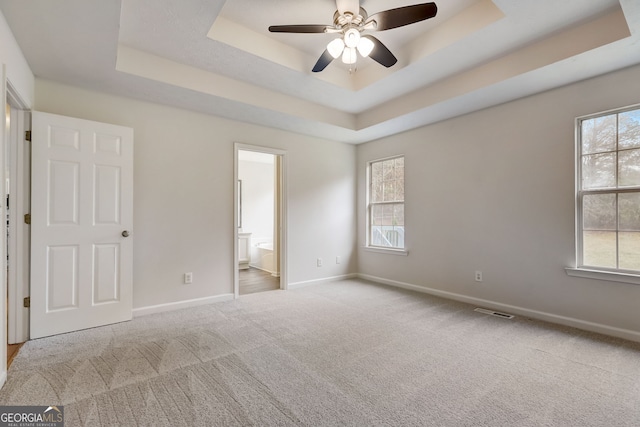 unfurnished bedroom featuring a tray ceiling and multiple windows