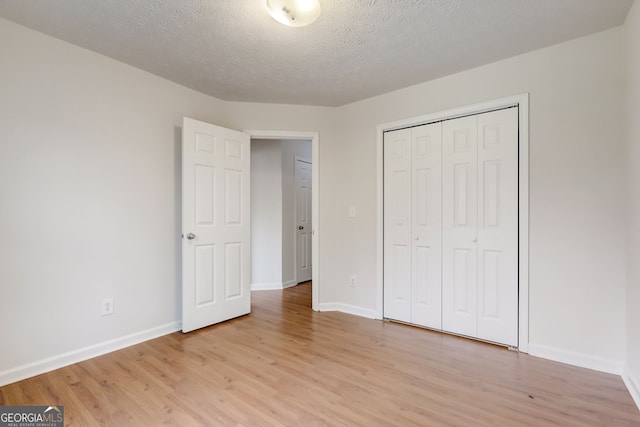 unfurnished bedroom featuring a closet, light hardwood / wood-style floors, and a textured ceiling