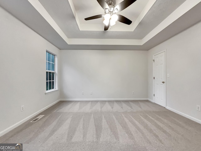 unfurnished room with light colored carpet, a raised ceiling, and ceiling fan