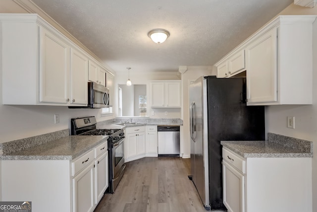 kitchen featuring white cabinetry, light wood-type flooring, a textured ceiling, and appliances with stainless steel finishes