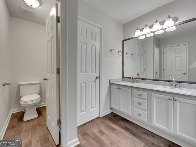 bathroom with wood-type flooring, vanity, and toilet