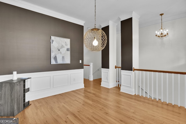 unfurnished room with hardwood / wood-style floors, ornamental molding, and a notable chandelier