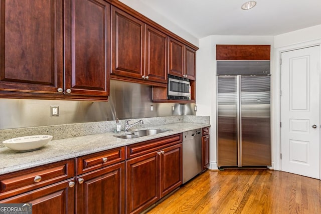 750 Park Ave NE Unit 8E, Atlanta, GA 30326 - kitchen featuring appliances with stainless steel finishes, a sink, wood finished floors, light stone countertops, and dark brown cabinets