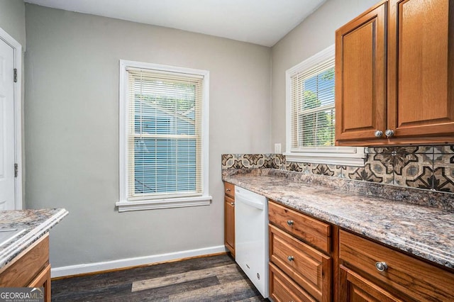 kitchen featuring dishwasher, decorative backsplash, dark hardwood / wood-style floors, and dark stone counters