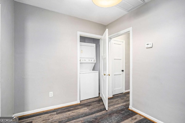 laundry room with dark wood-type flooring and stacked washer and clothes dryer