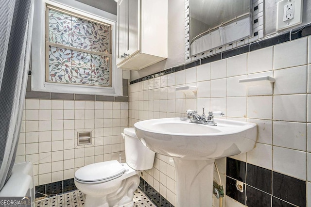 bathroom with walk in shower, tile patterned floors, toilet, and tile walls