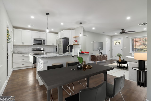 kitchen with light stone counters, stainless steel appliances, ceiling fan, white cabinets, and hanging light fixtures