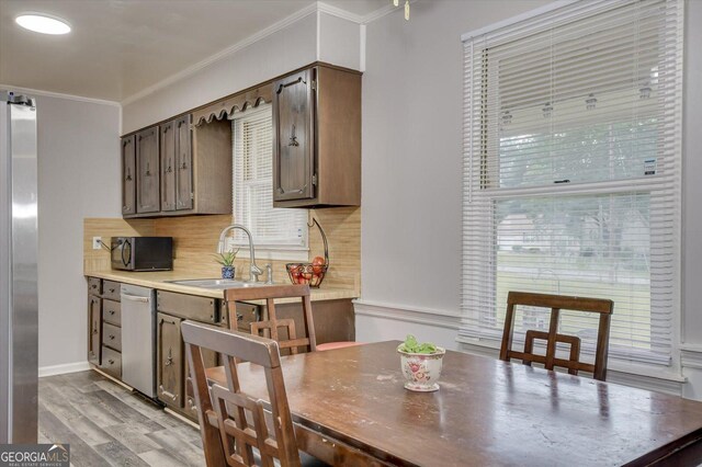 kitchen with light wood-type flooring, tasteful backsplash, stainless steel appliances, crown molding, and sink