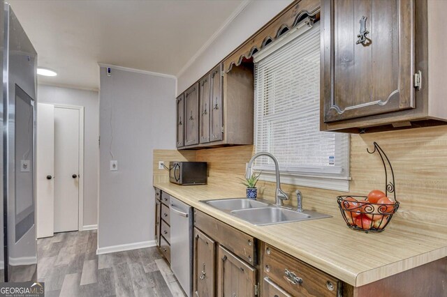 kitchen with sink, stainless steel dishwasher, backsplash, crown molding, and light wood-type flooring