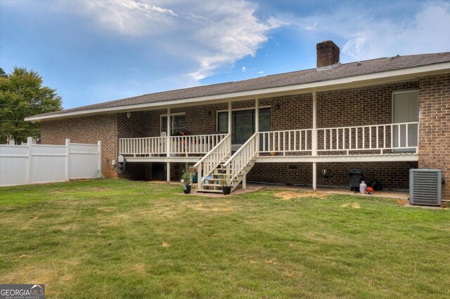 back of property featuring a lawn and central AC