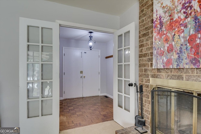 entrance foyer featuring french doors, parquet floors, and a brick fireplace